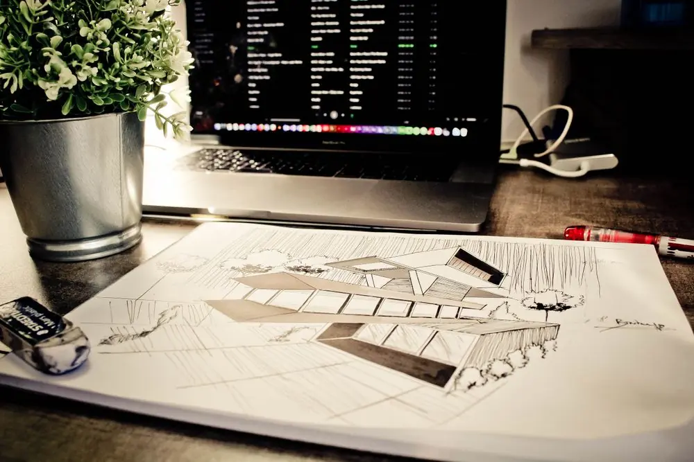 Architectural workspace showing design blueprints, laptop interface, and drawing instruments